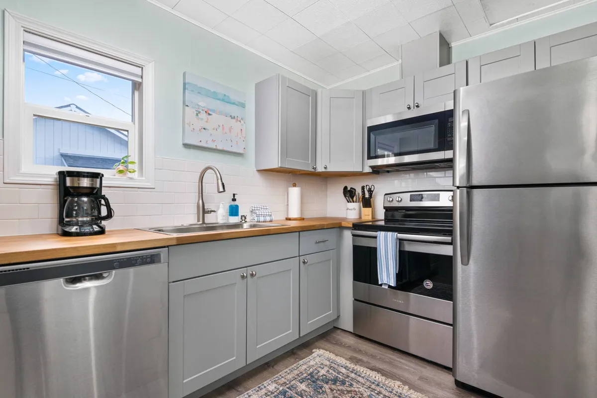 A modern kitchen with stainless steel appliances, a wooden countertop, and colorful wall art, inviting both solo enjoyment and communal gatherings over coffee or a meal. The setup is conducive to shared experiences, like breakfast with neighbors or family.