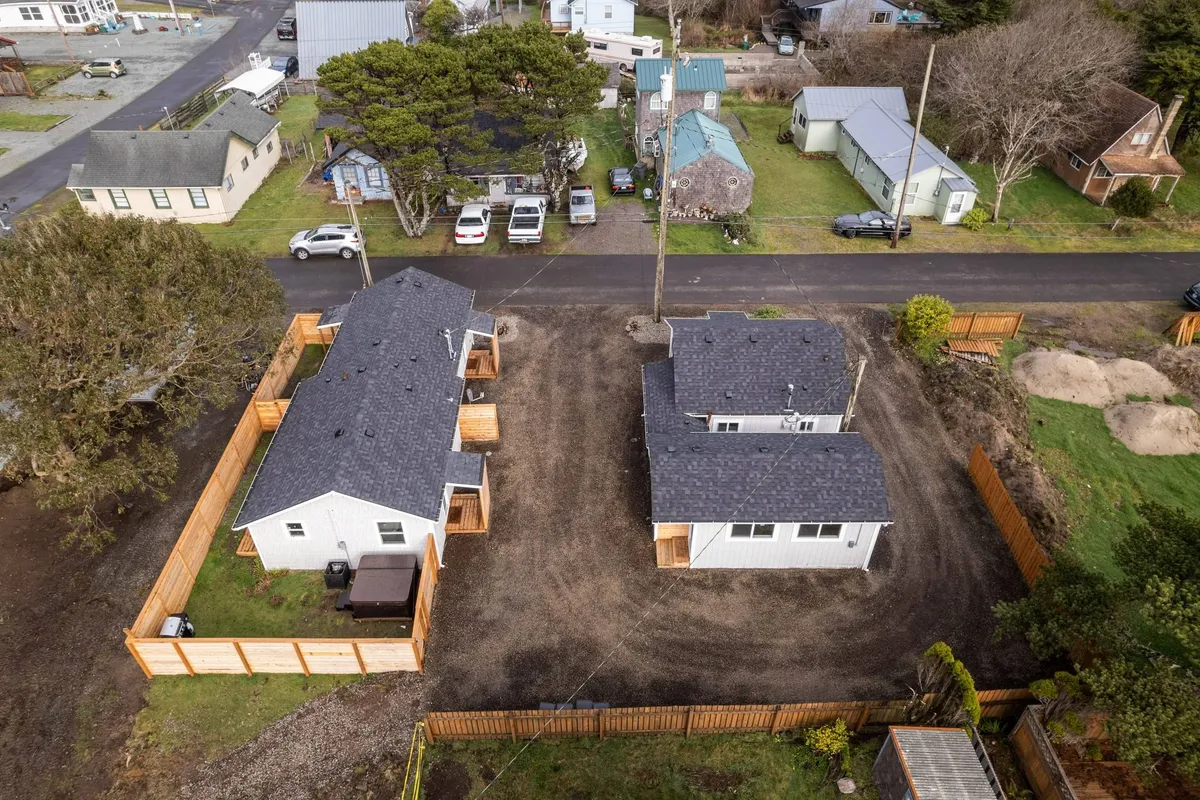 A complementary exterior perspective highlighting two houses with a fenced yard and mature trees, suggesting privacy and relaxation after a day of exploring. The homes feel both connected and slightly set apart, perfect for groups booking neighboring units.